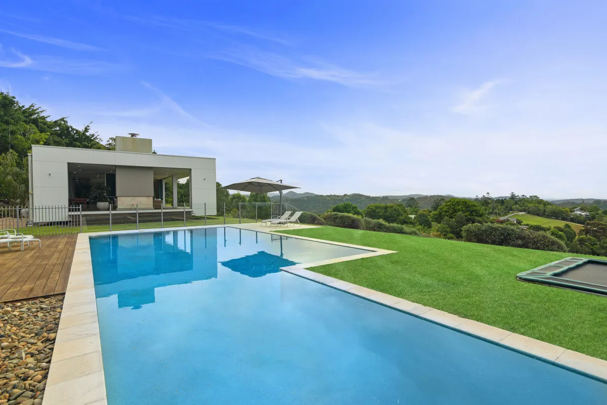 Pool at Brocks Road with a white pavilion, sun loungers under an umbrella and lawn running out to hinterland views.