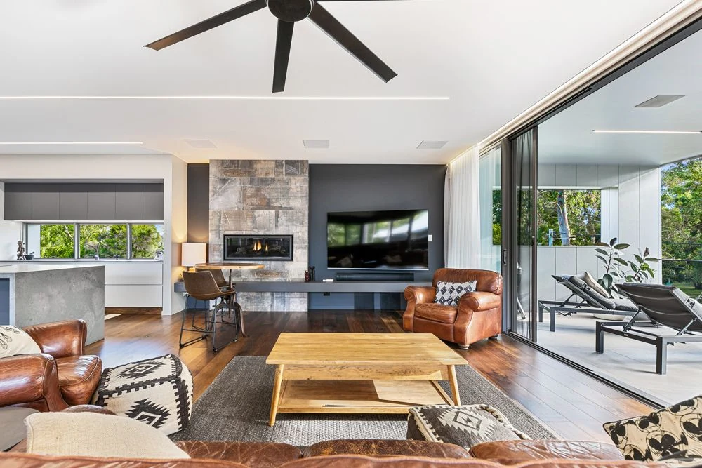 Living room television and floating shelf beside open doors to the covered deck.