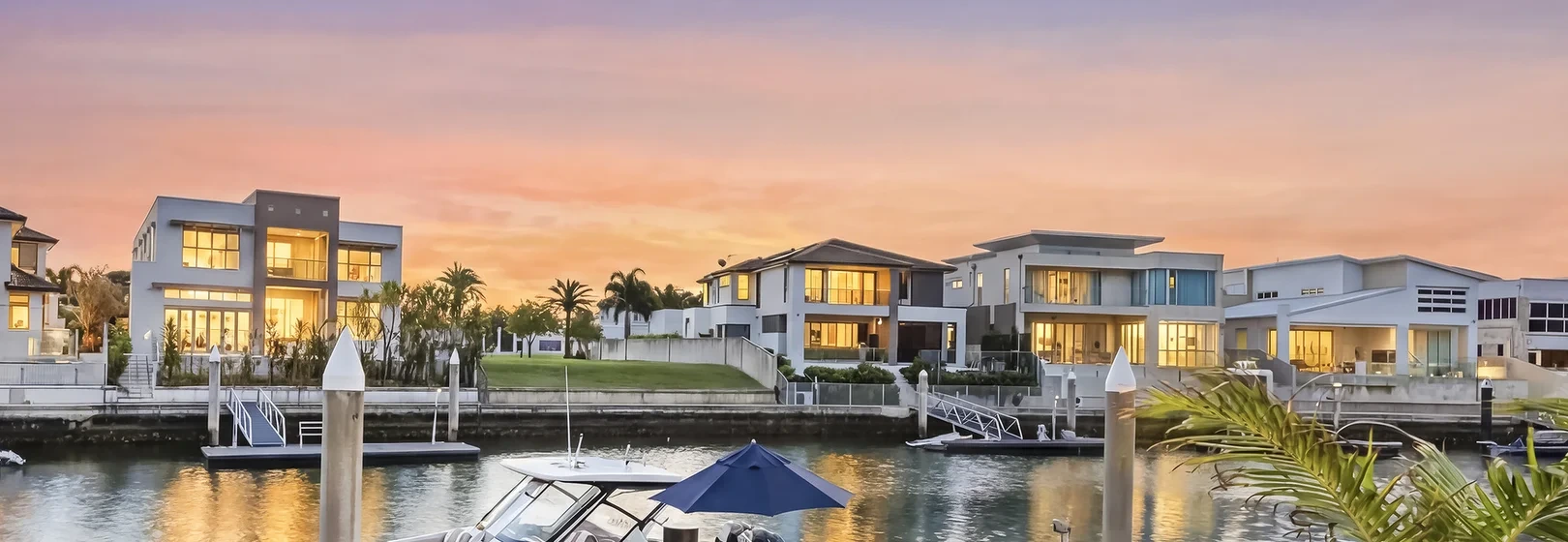 Waterfront homes at dusk on a Gold Coast canal, reflected in the water.